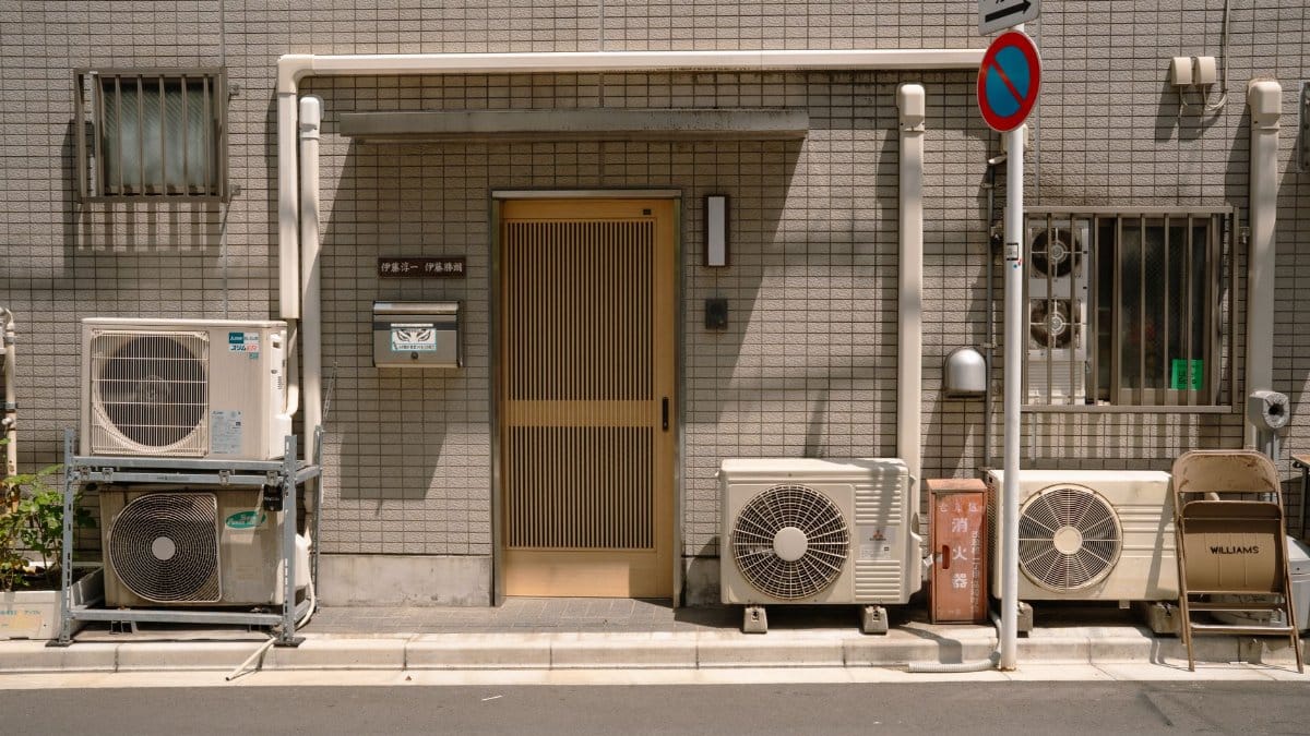 A minimalist facade with air conditioners and a no parking sign in Tokyo, Japan.