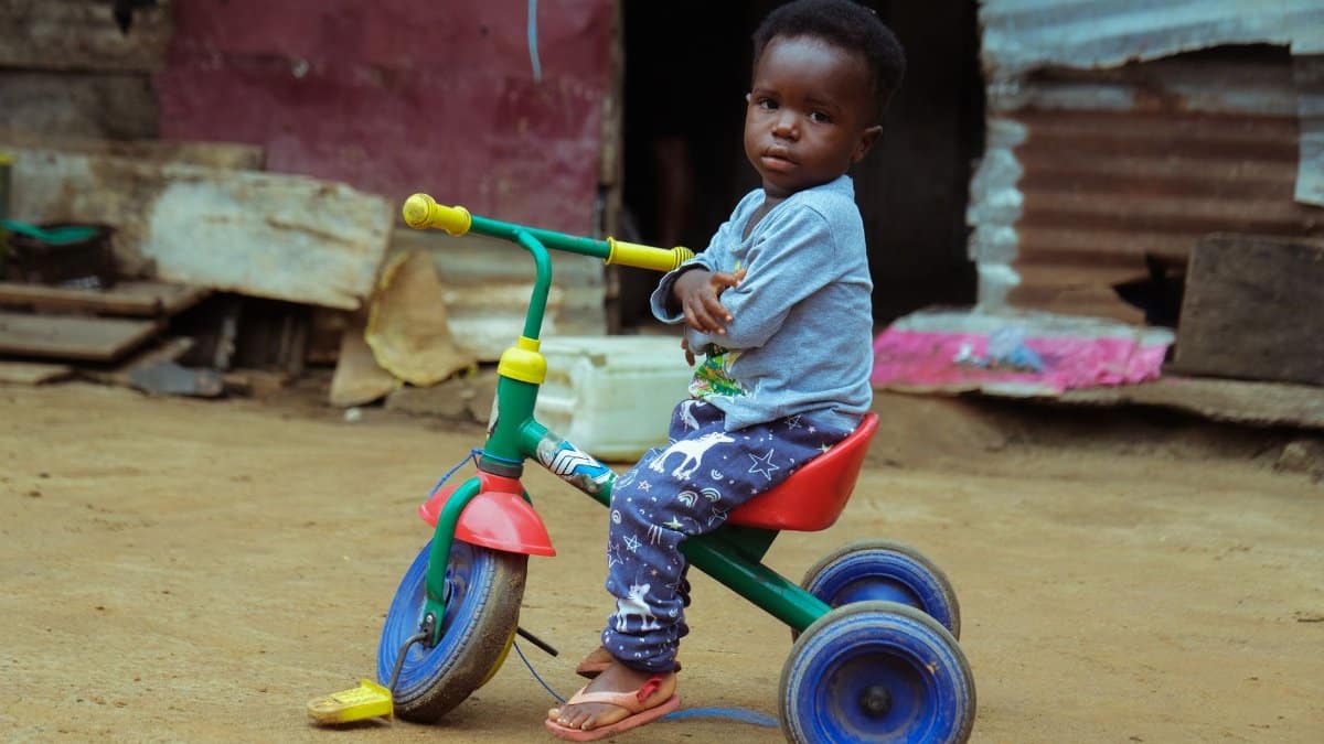 Young child on a colorful tricycle, playing in an urban setting, Monrovia, Liberia.