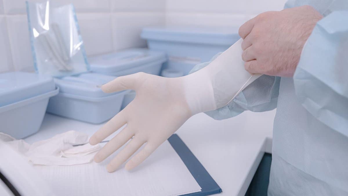A medical practitioner wearing latex gloves in a clinical setting ensures cleanliness.