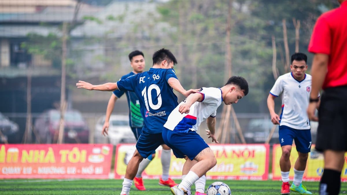 Local soccer players engaged in a dynamic match on an artificial turf field in Hà Nội, Việt Nam.