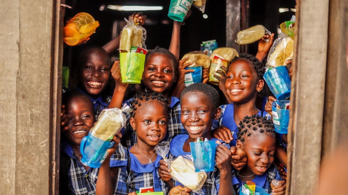 Group of happy children holding food packages and smiling outdoors.
