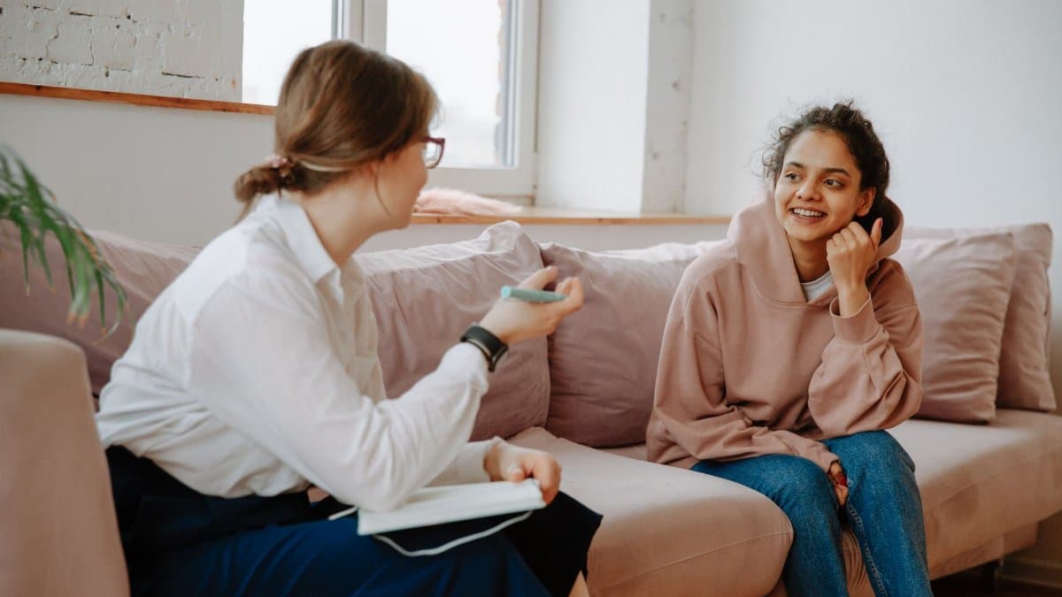 A therapist and young client engaging in a warm counseling session on a cozy sofa.