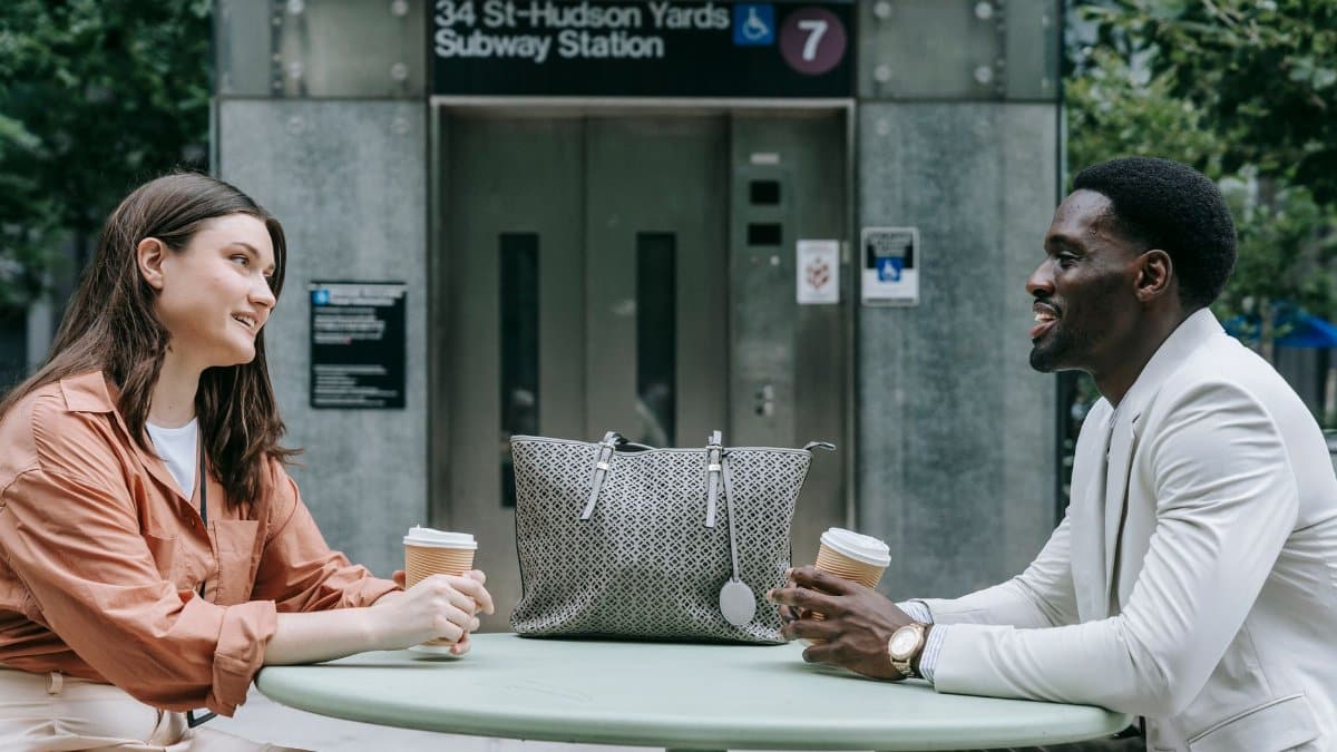 Two people chatting over coffee outside 34 St-Hudson Yards Subway Station in NYC.