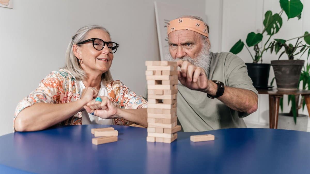 Senior man and woman playing Jenga, creating a fun and engaging atmosphere indoors.