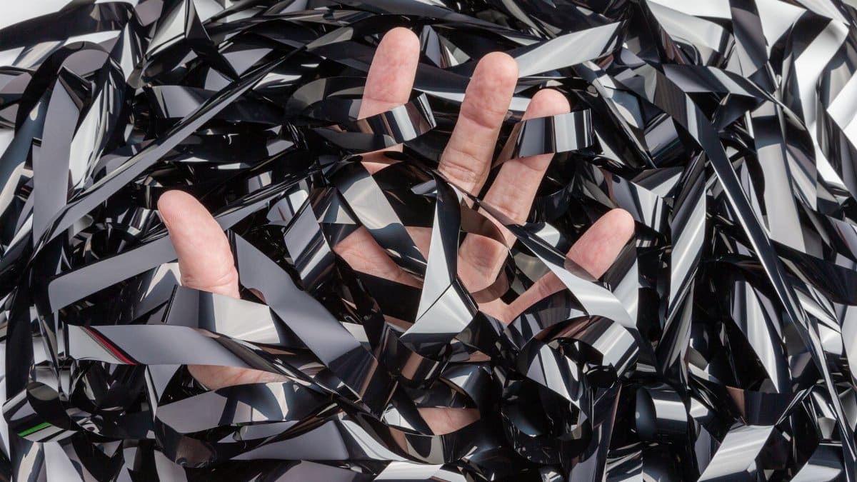 A hand tangled in a chaotic mess of analog film tape, symbolizing creative expression.