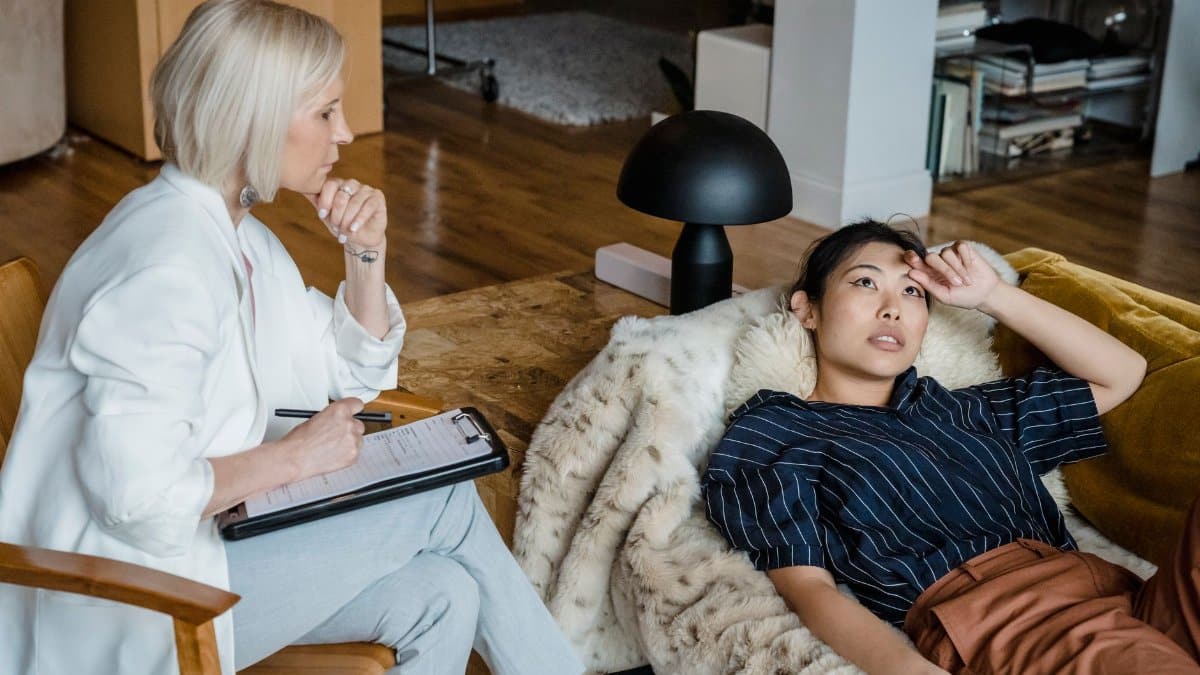 Psychologist listens attentively to a stressed young woman during therapy session.