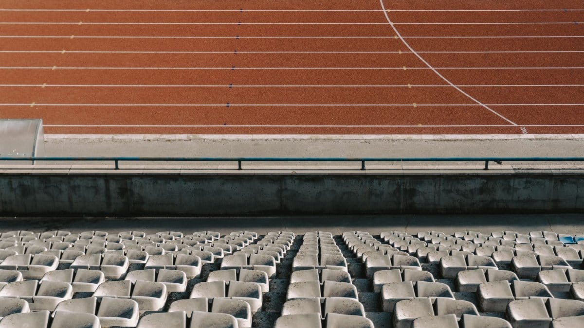 Rows of empty stadium seats with a view of the running track under daylight.