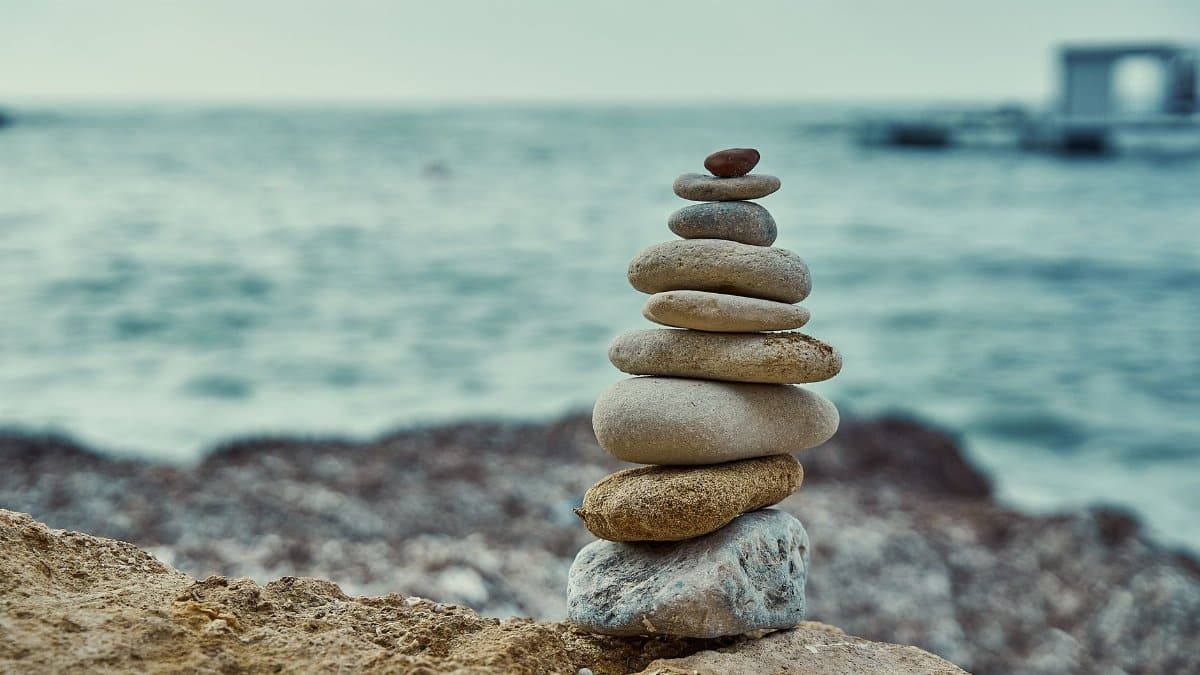 Peaceful stone stack on a beach with a blurred ocean background and serene atmosphere.