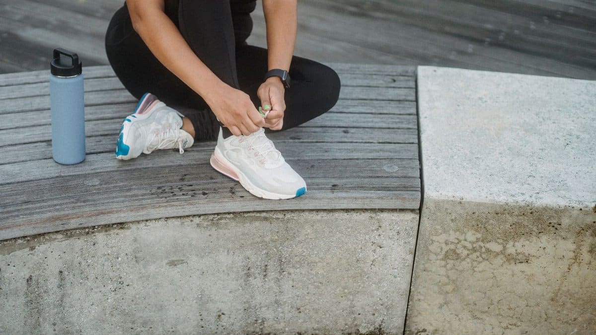 Active woman ties her sneakers on a concrete bench, ready for workout.