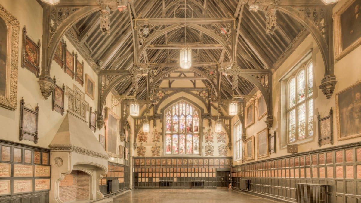 A beautiful historic hall in England featuring ornate timber architecture and stained glass windows.