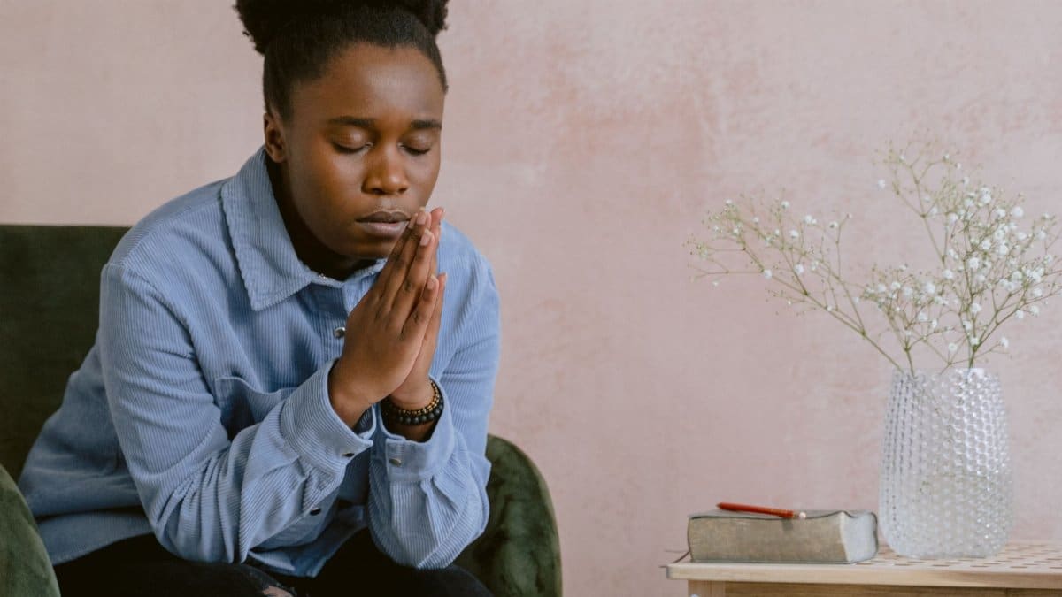 A woman in quiet contemplation, praying with hands clasped, embodying faith and serenity.