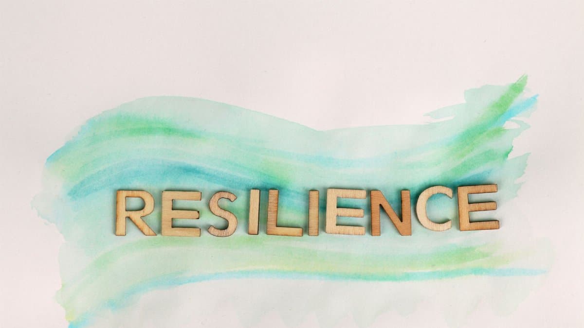 The word 'Resilience' painted with green watercolor and wooden letters on a white background.