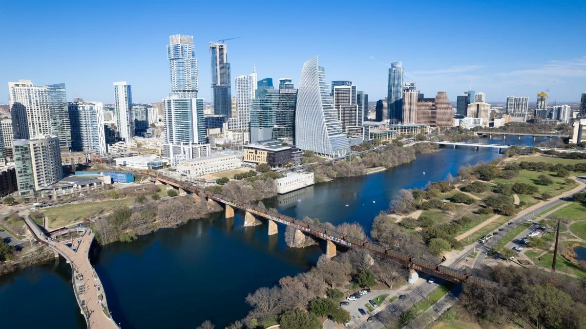 Aerial view of Austin, Texas skyline with landmarks including river and footbridge.