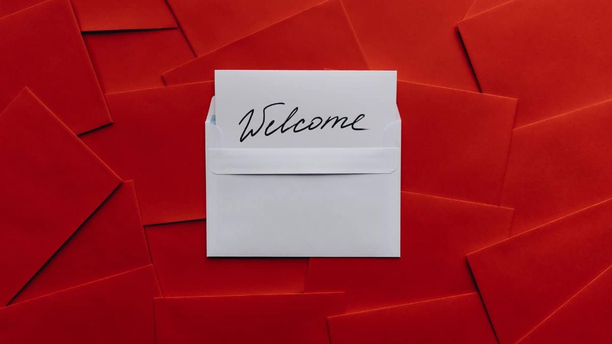 A white card with 'Welcome' text in an envelope against a red envelope background.