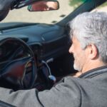 Senior couple enjoying a sunny drive in a convertible through scenic Portugal.