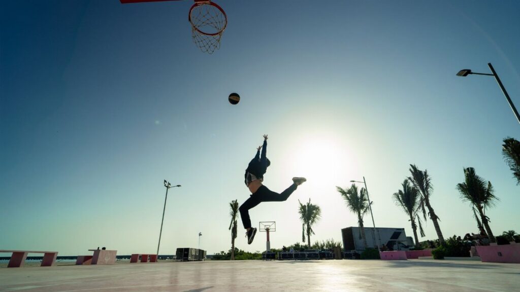 Silhouette of a basketball player jumping for a dunk at sunrise in Progreso, Mexico.