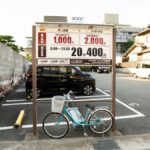 A bicycle parked in an empty parking lot in Kyoto, Japan, with traditional architecture in the background.