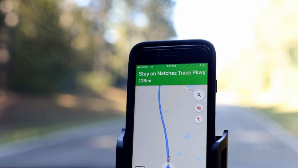 Smartphone displaying GPS navigation route on Natchez Trace Parkway inside a car.