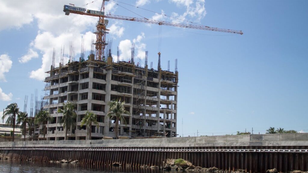 High-rise building under construction with a tower crane in a city setting.