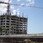 High-rise building under construction with a tower crane in a city setting.