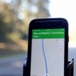Smartphone displaying GPS navigation route on Natchez Trace Parkway inside a car.