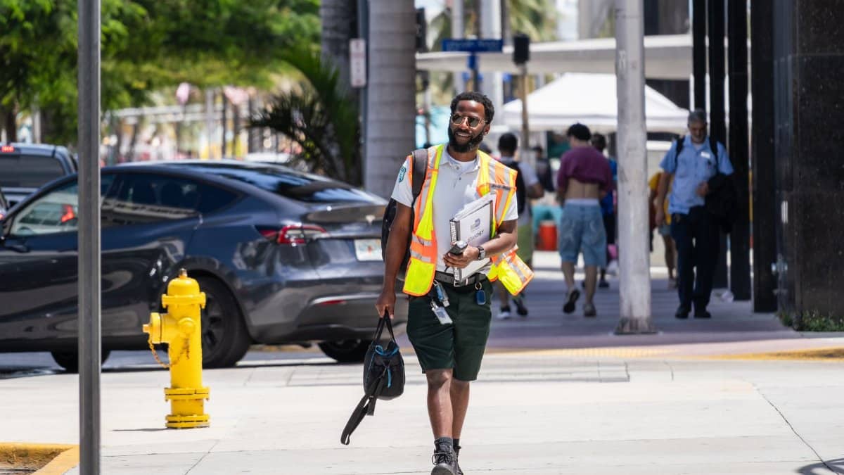 Construction worker walks confidently on Miami Beach street in summer.