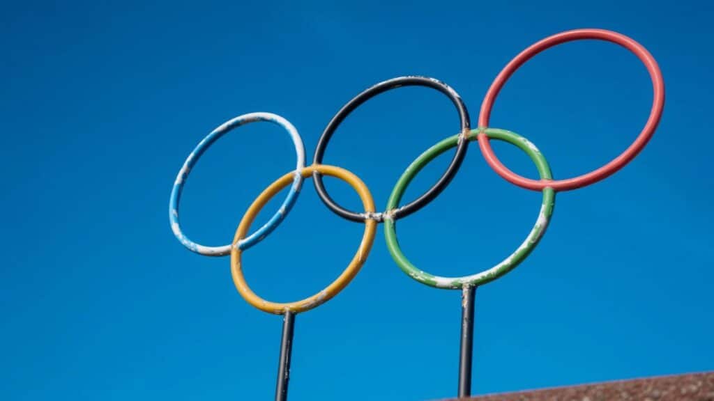 The iconic Olympic rings stand against a vibrant blue sky, symbolizing global unity and sportsmanship.