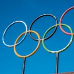 The iconic Olympic rings stand against a vibrant blue sky, symbolizing global unity and sportsmanship.