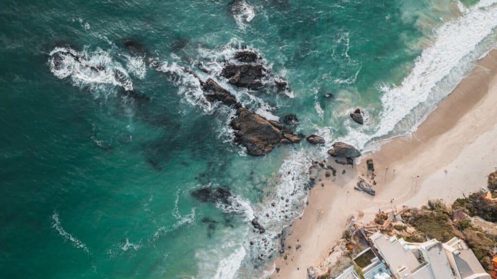 A stunning aerial view of Laguna Beach, showcasing waves, rocks, and coastal buildings.