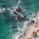 A stunning aerial view of Laguna Beach, showcasing waves, rocks, and coastal buildings.