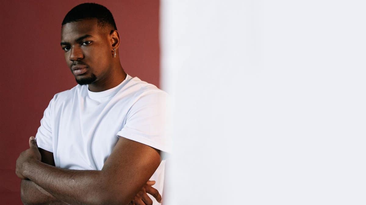 African American man in a white shirt posing confidently in a studio setting.