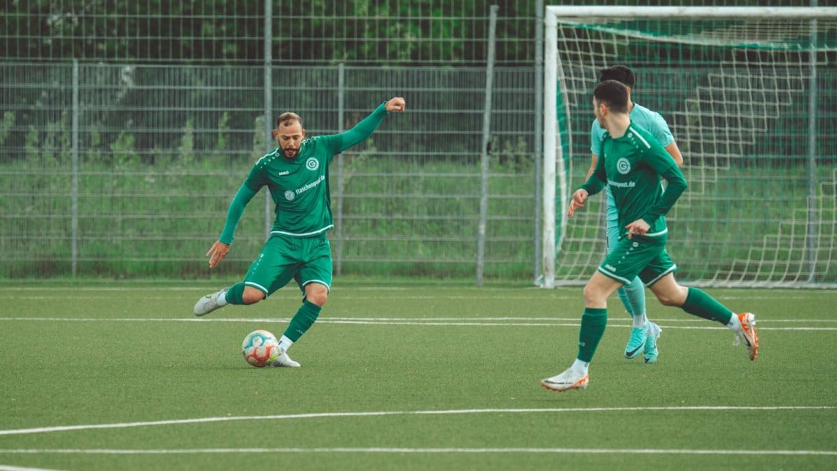 Players in green uniforms engage in a dynamic soccer match on a grassy field.