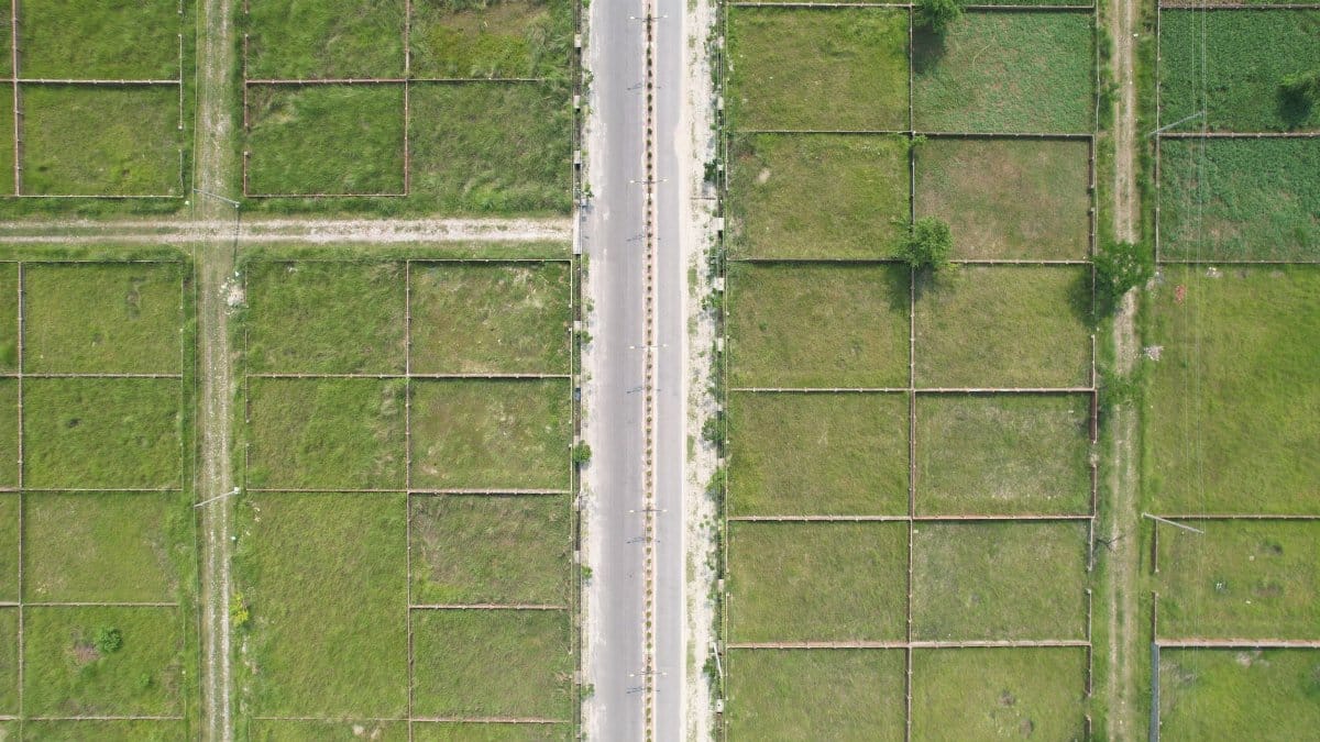 Aerial shot of lush green fields and road in rural Dhaka, Bangladesh.