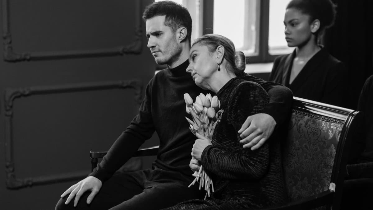 A somber black and white image capturing a grieving family at a funeral.