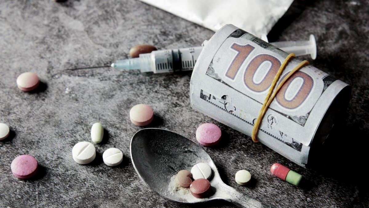 Symbolic representation of drug addiction and financial cost with pills and money.