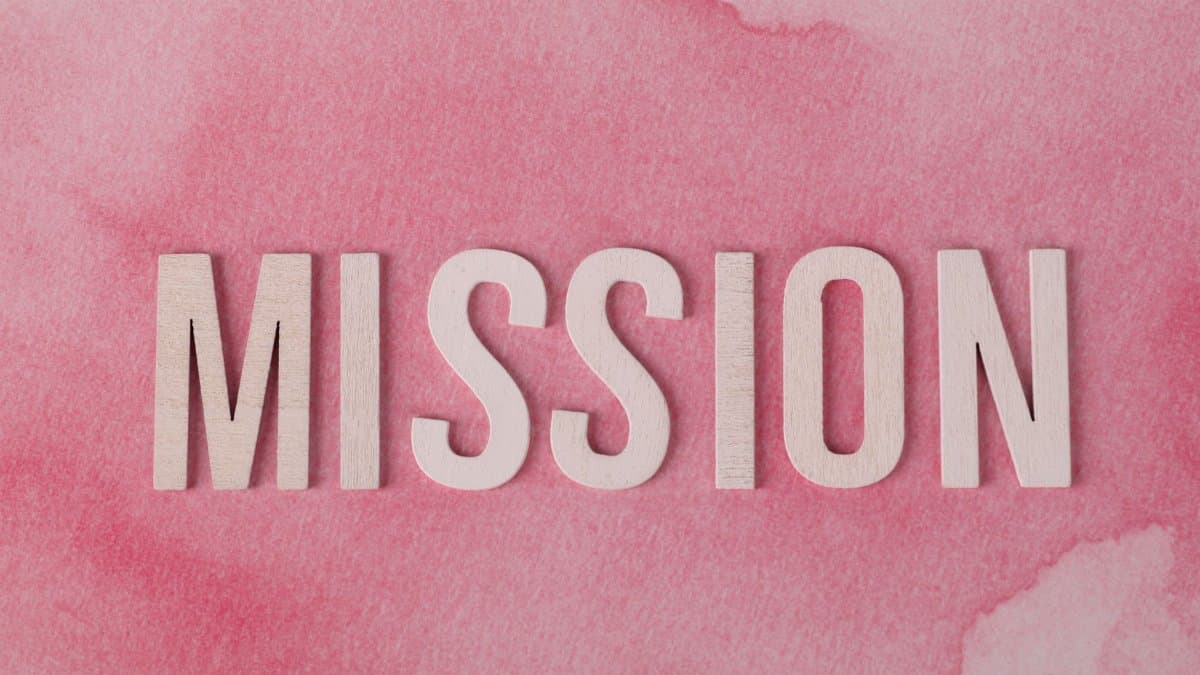 Wooden letters spelling 'MISSION' on a soft pink watercolor background.