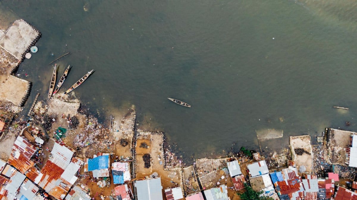 Aerial view capturing a coastal settlement with boats on a calm shore, showcasing vibrant roofs.