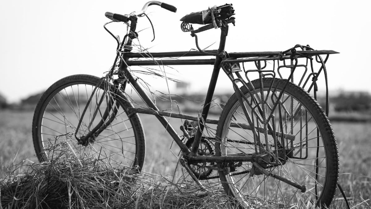 Black and white image of an old bicycle in a grassy field in Burundi.