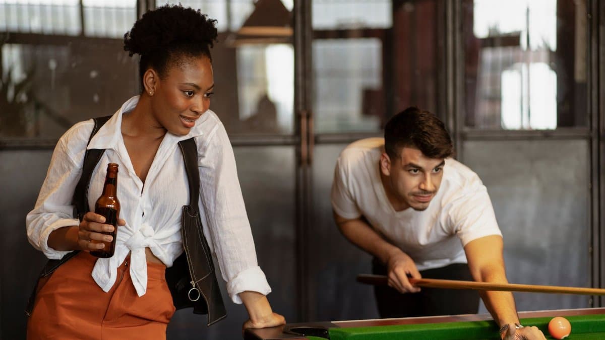 Young adults enjoying a casual billiards game in a modern bar. Perfect for leisure and lifestyle themes.