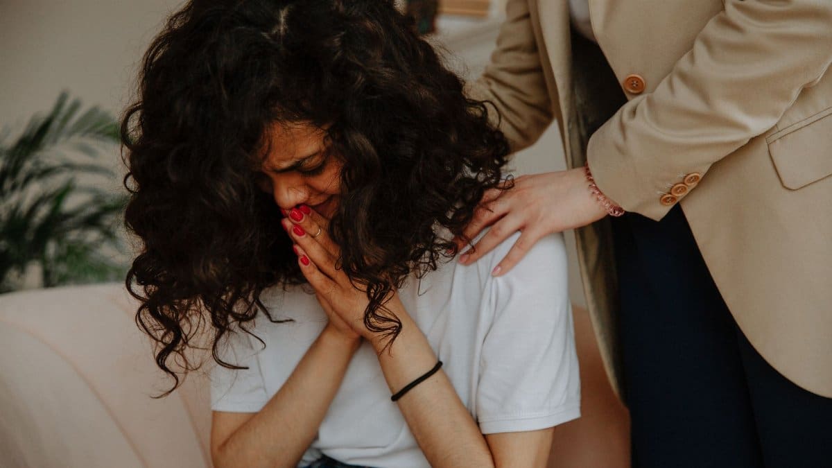 A young woman receiving comforting and emotional support during a therapy session.