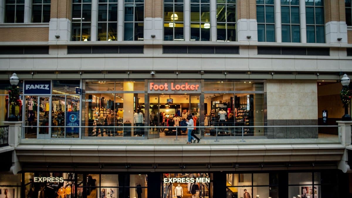 View of a shopping mall interior featuring Foot Locker and Express stores with people walking by.