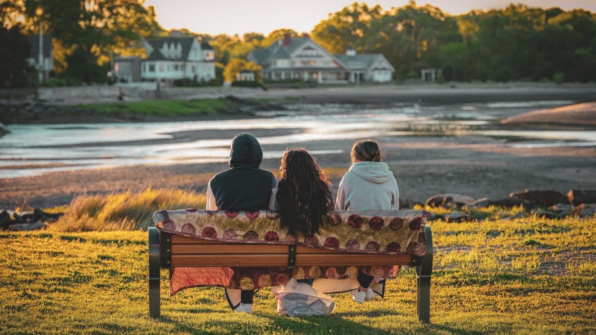 Three friends sit on a bench at dawn, enjoying a peaceful view in Cove Island Park, Stamford, Connecticut.