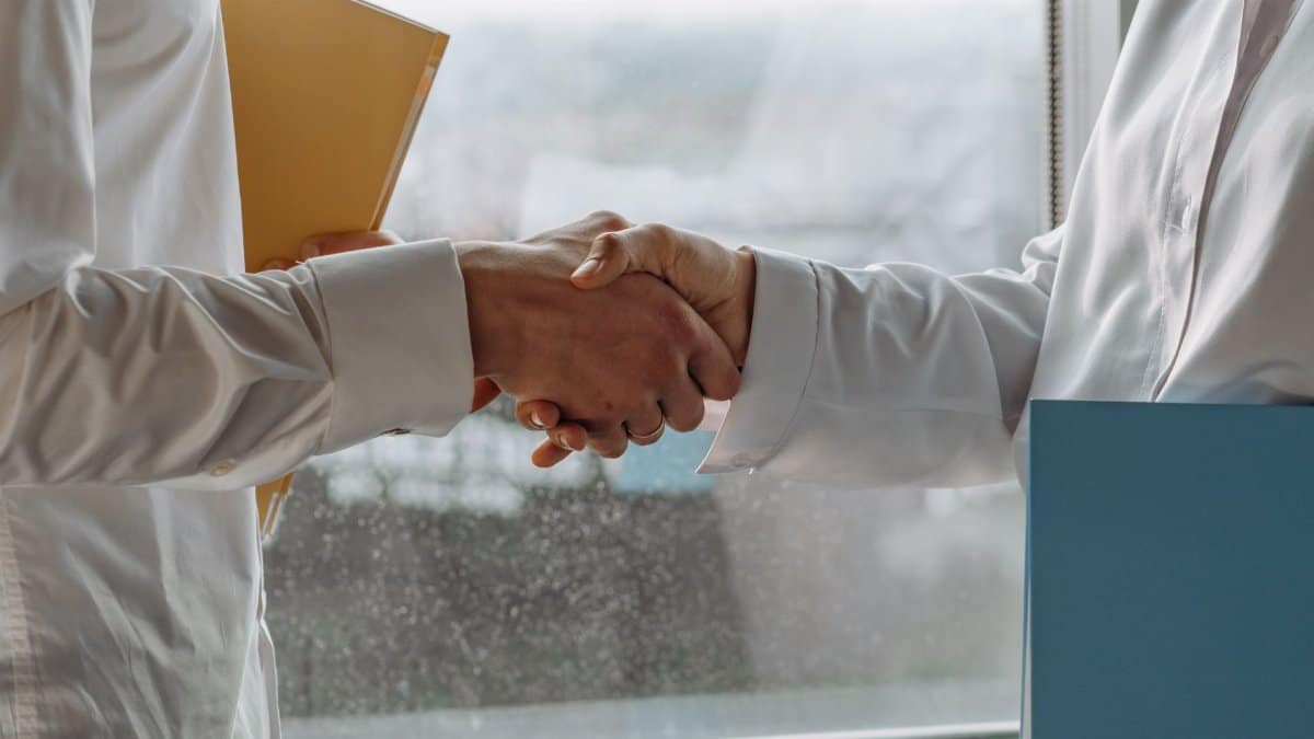 Two business professionals shaking hands indoors, symbolizing agreement.