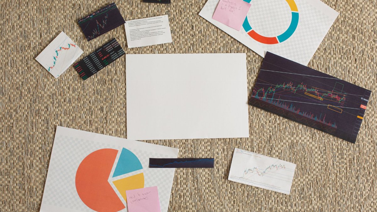 Flat lay of financial charts and sticky notes on a textured surface, ideal for planning and analysis concepts.