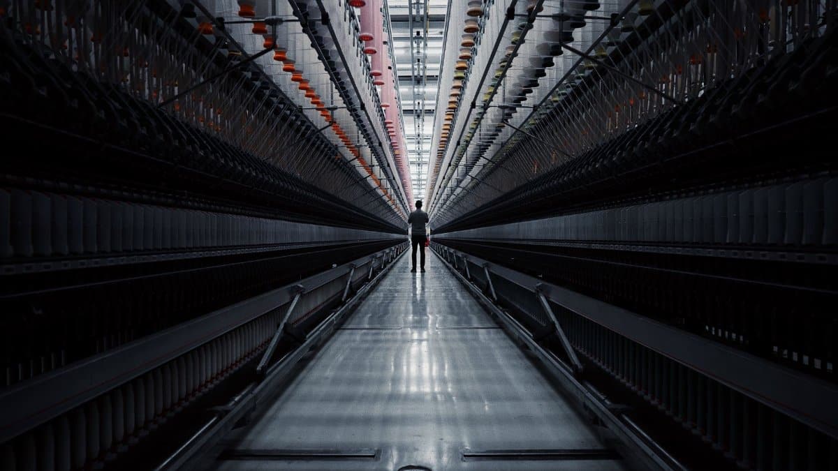 A solitary man stands inside a vast industrial tunnel, emphasizing symmetry and perspective.