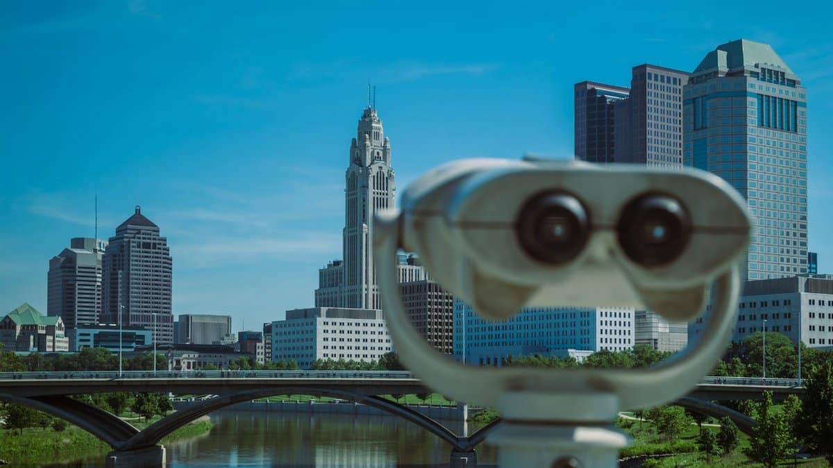 A coin operated telescope focusing on a city skyline with tall buildings and a bridge.