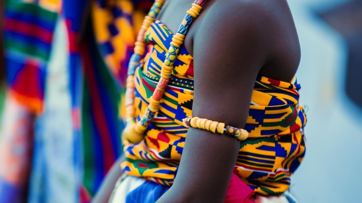 Vibrant traditional Ghanaian attire with beads and kente cloth, highlighting cultural identity.