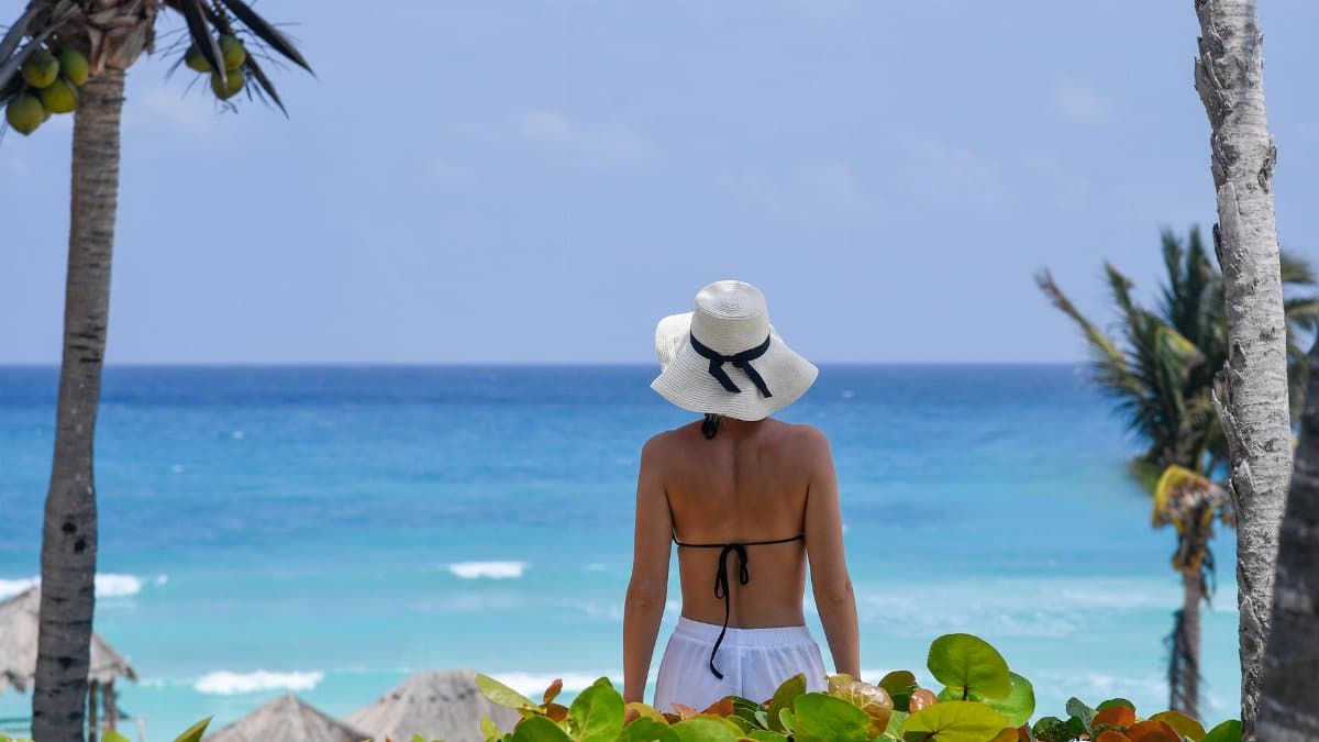 Back view of a woman with sun hat looking at the ocean in Cancún, Mexico.