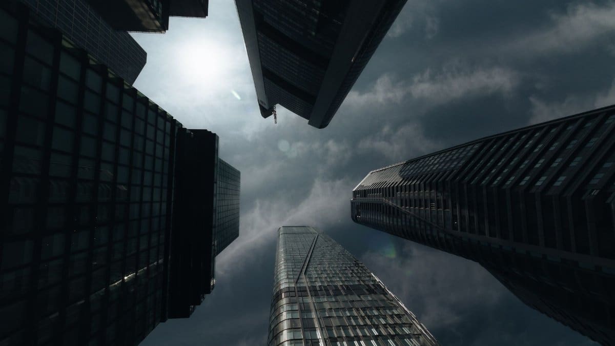 Looking up at tall skyscrapers against a cloudy sky, creating a dramatic urban scene.