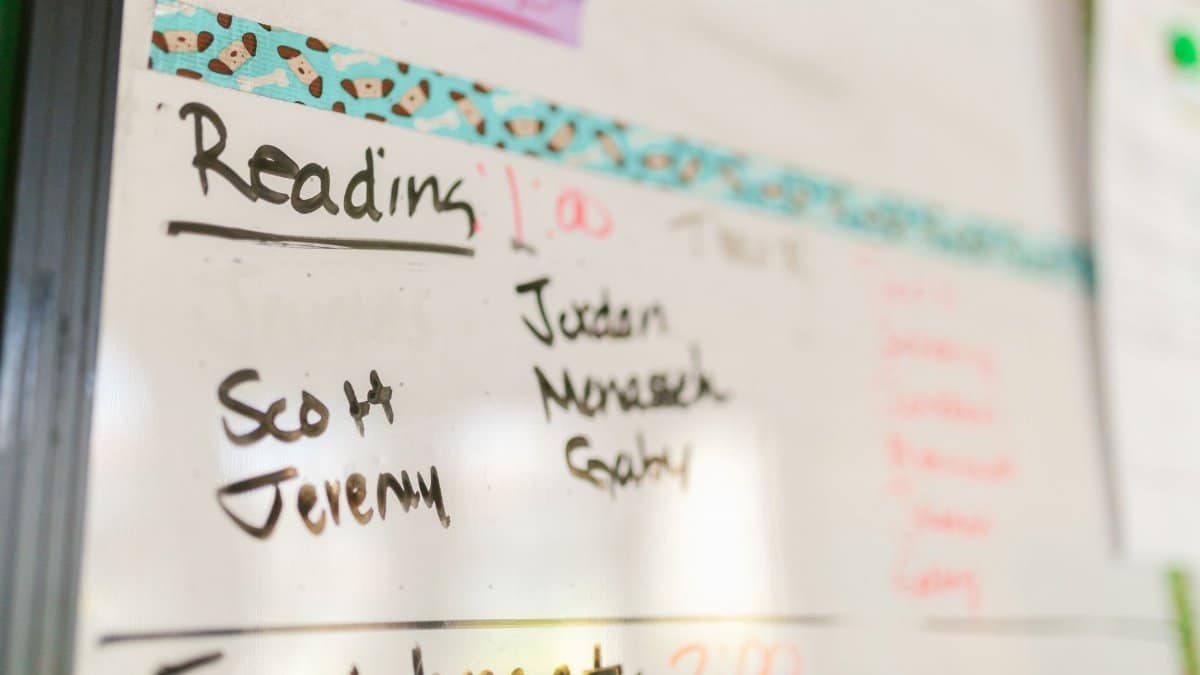 Close-up of a classroom whiteboard with names and reading schedule, ideal for education themes.